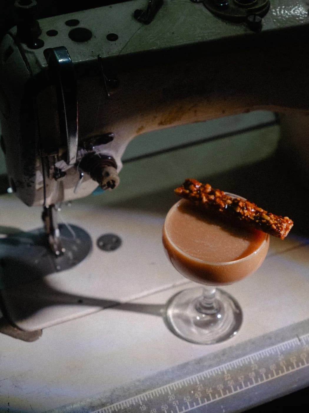 A coupe garnished with peanut brittle resting on an old sewing machine table